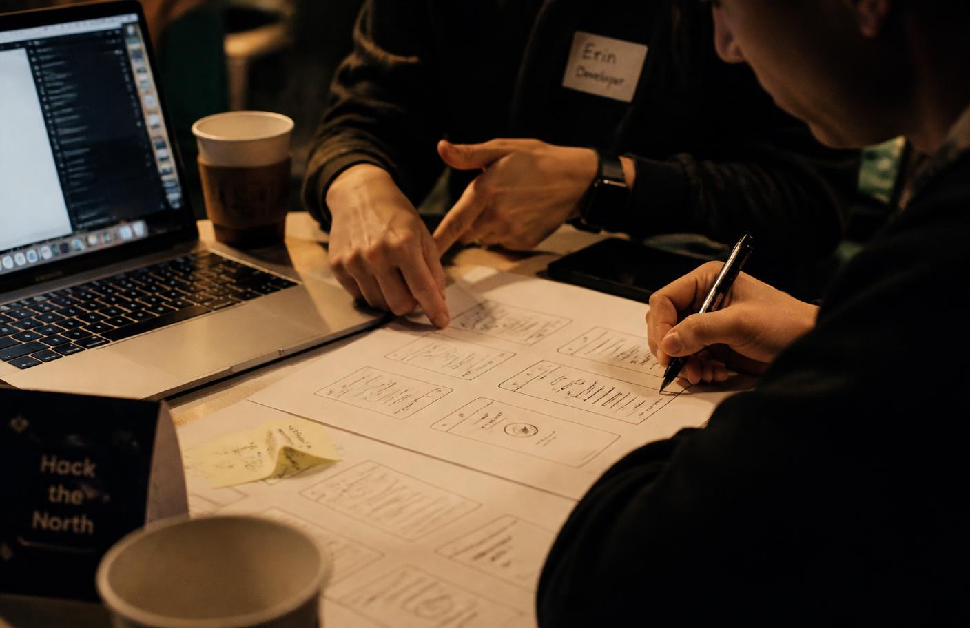 Équipe en hackathon travaillant sur des wireframes papier